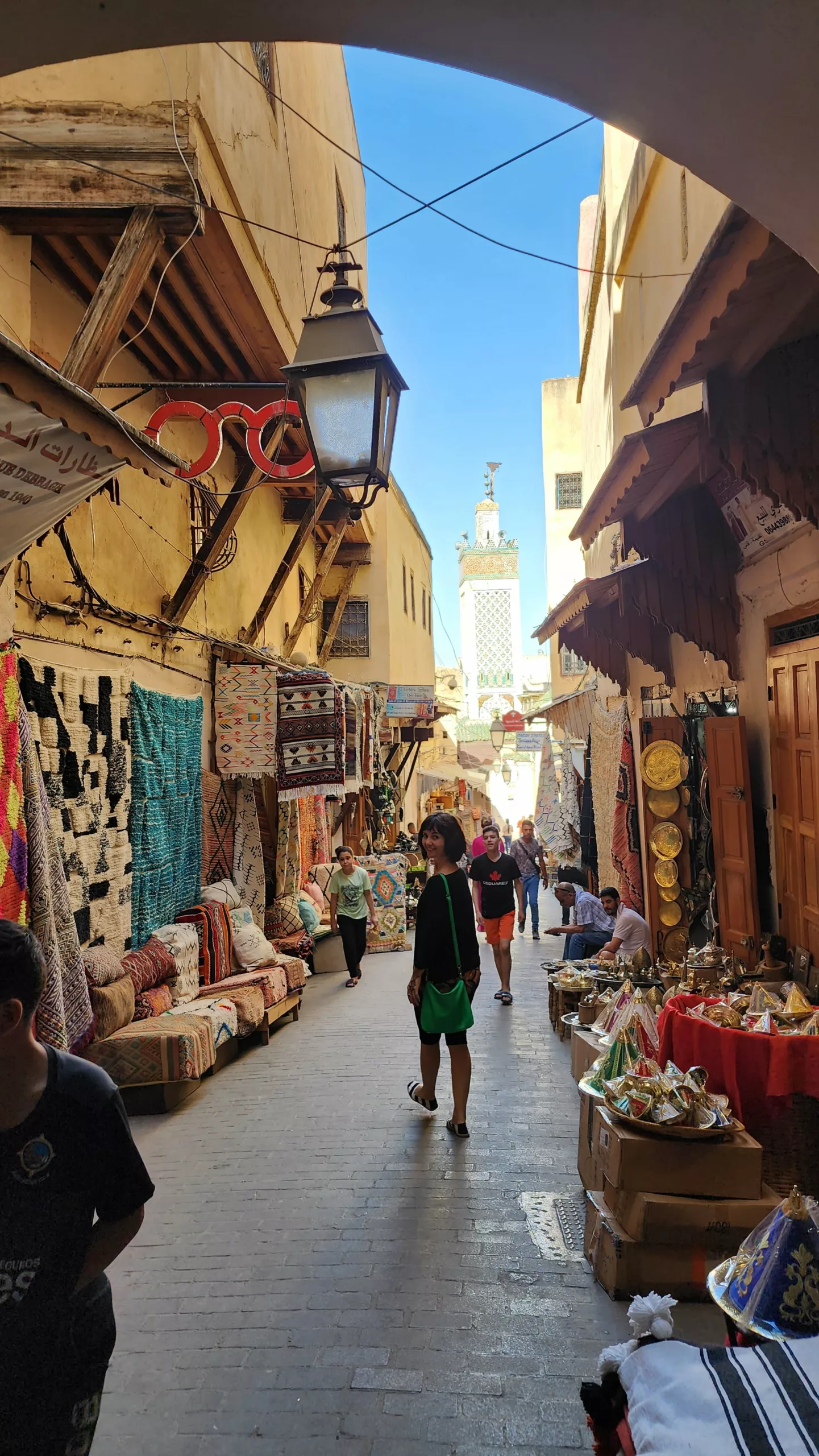 Rua estreita na medina de Marrakech, entre lojas, tapetes e lanternas