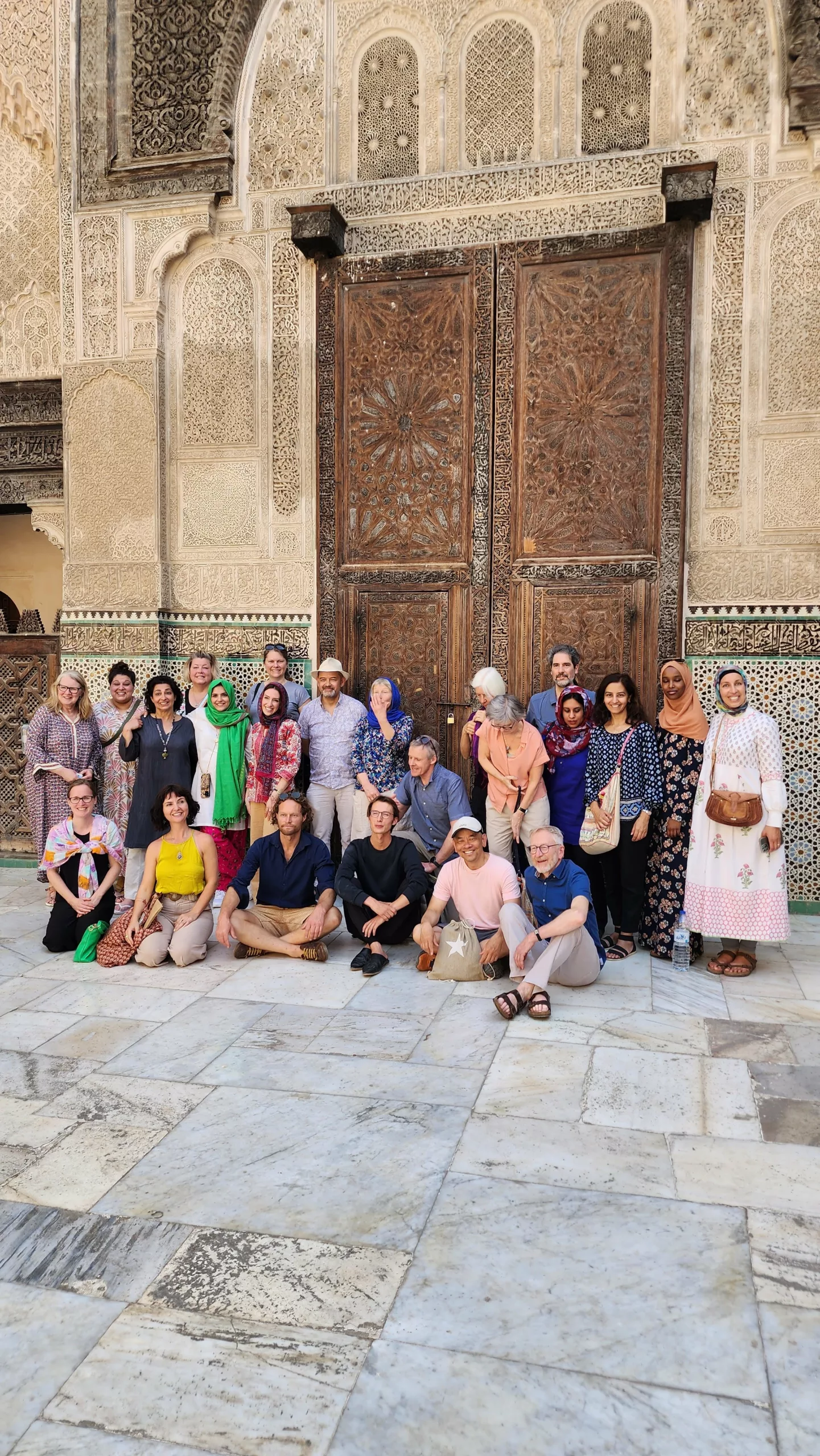 Grupo de participantes reunido diante das portas ornamentadas de uma madrasa em Marrakech
